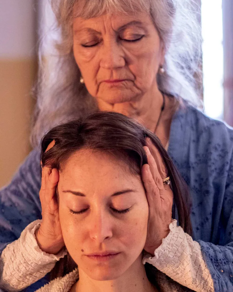 Oriana Viozzi mentre esegue un trattamento Shiatsu, con le mani appoggiate sulla testa di una persona distesa